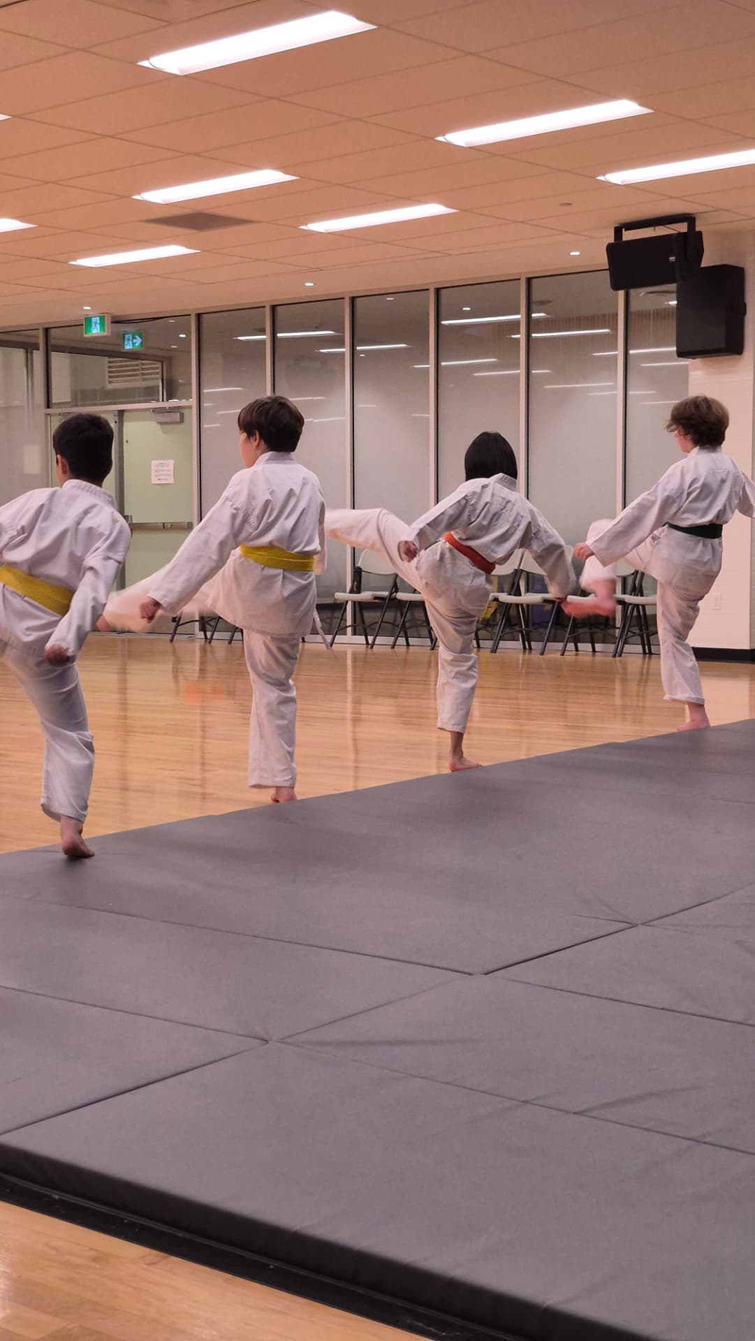 Children practise kicking techniques in a line during a karate class