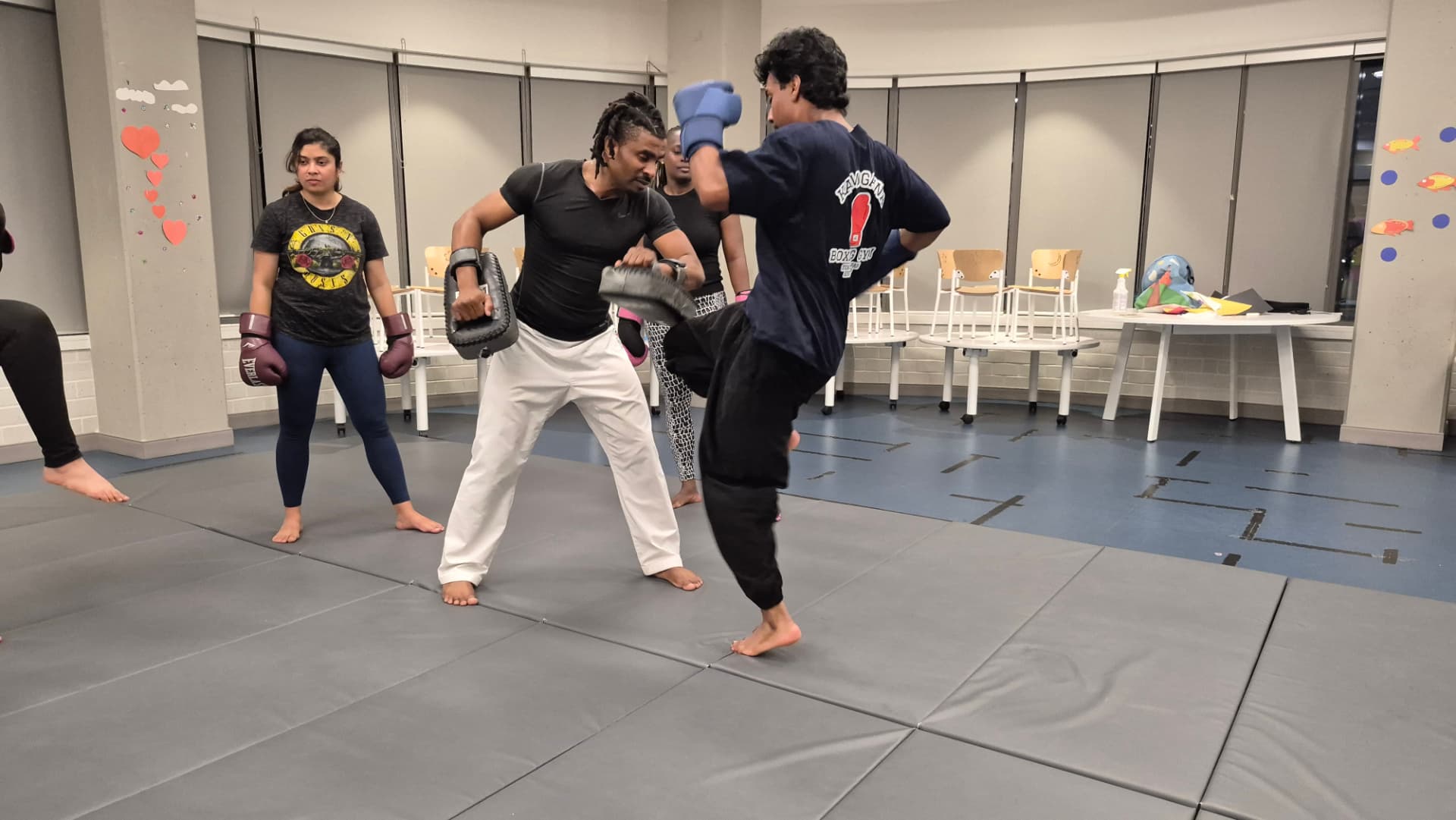 A group of adults train kickboxing combinations with an instructor holding pads