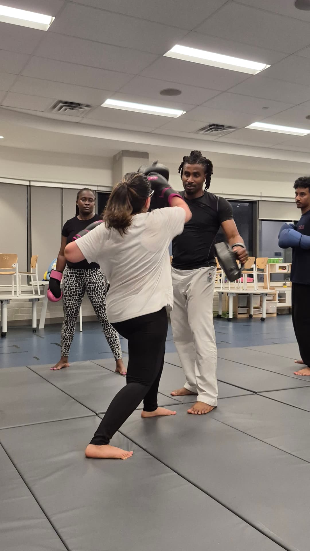An instructor coaches an adult student through a pad combination