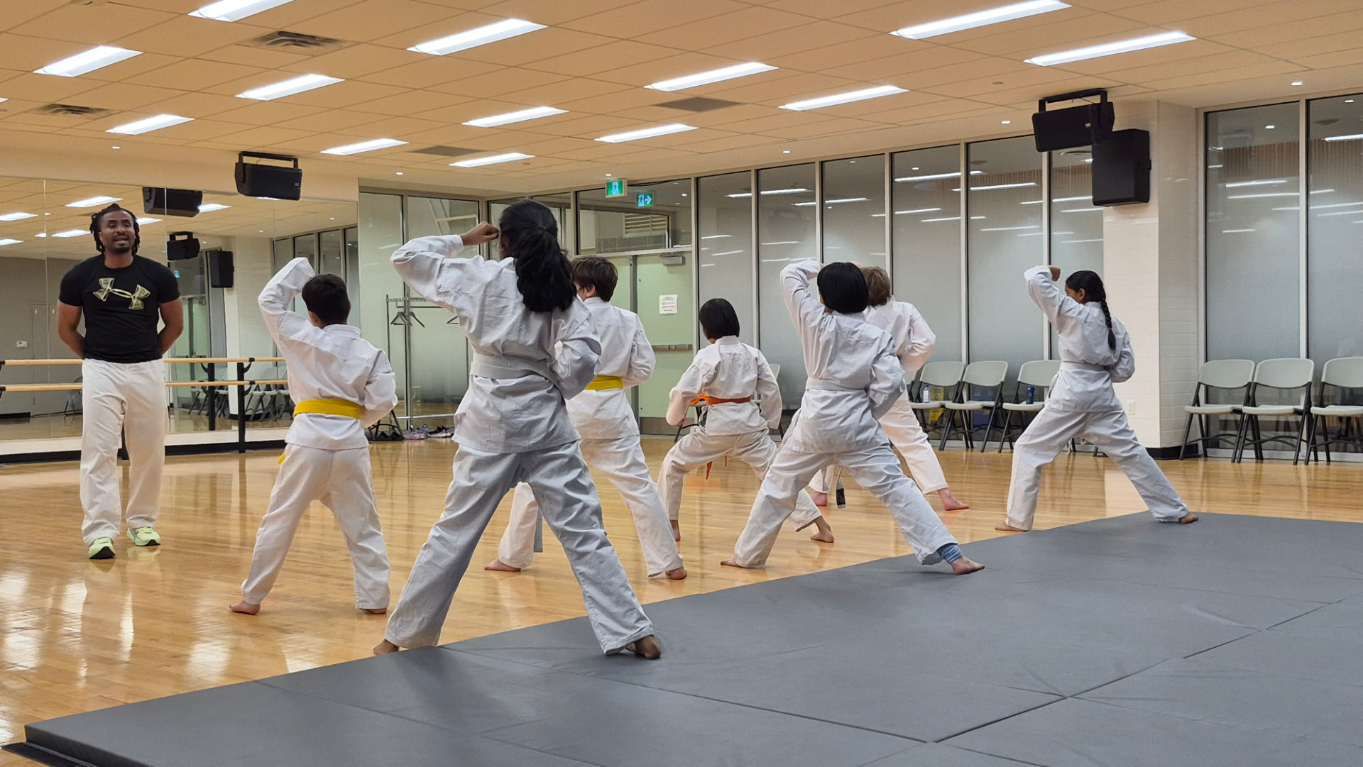 Children in white karate gi practising techniques together in a bright dojo