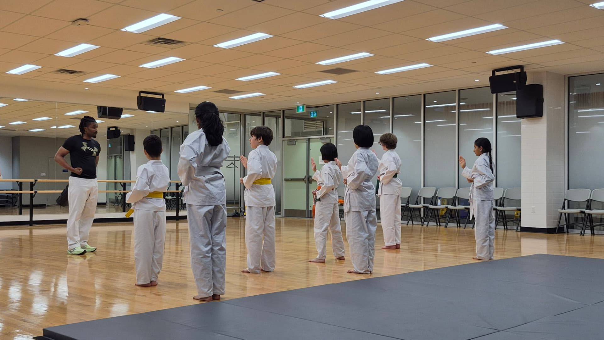 Young karate students stand in formation while listening to their instructor