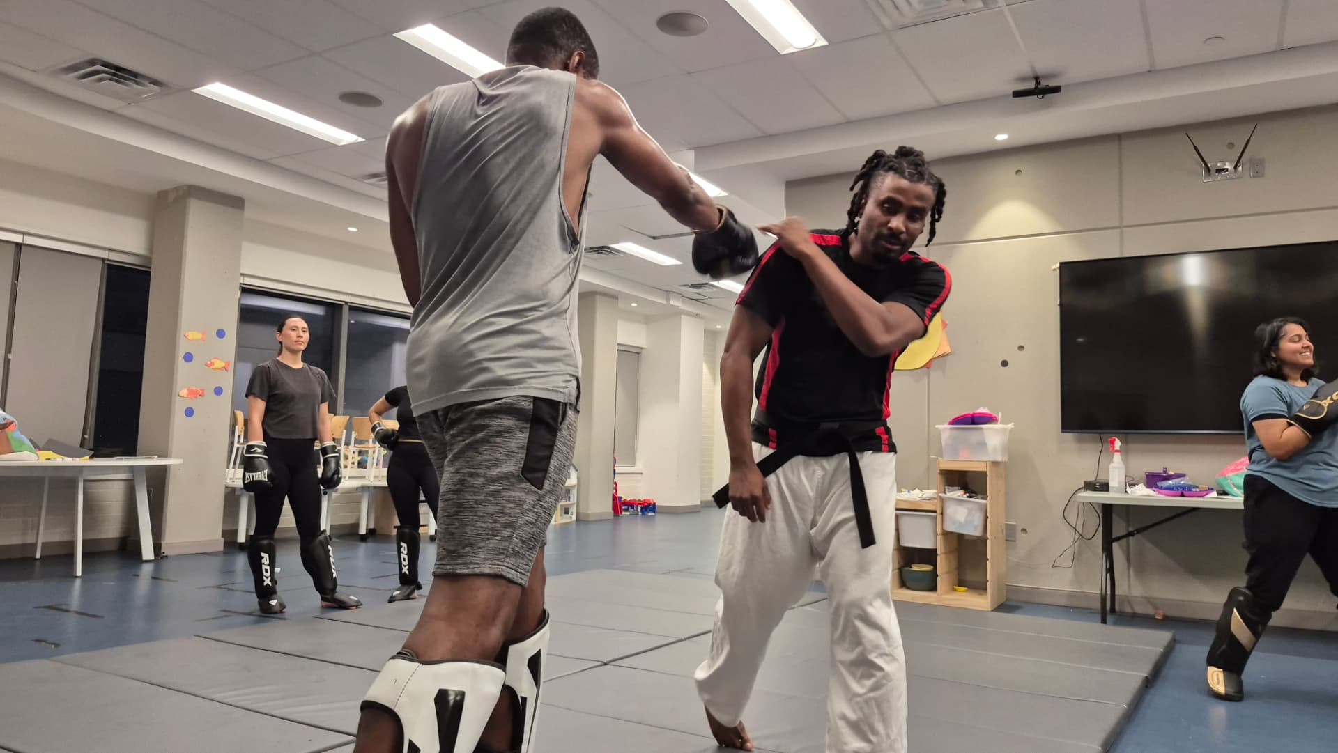 The instructor demonstrates a slip against a student's punch during a class drill